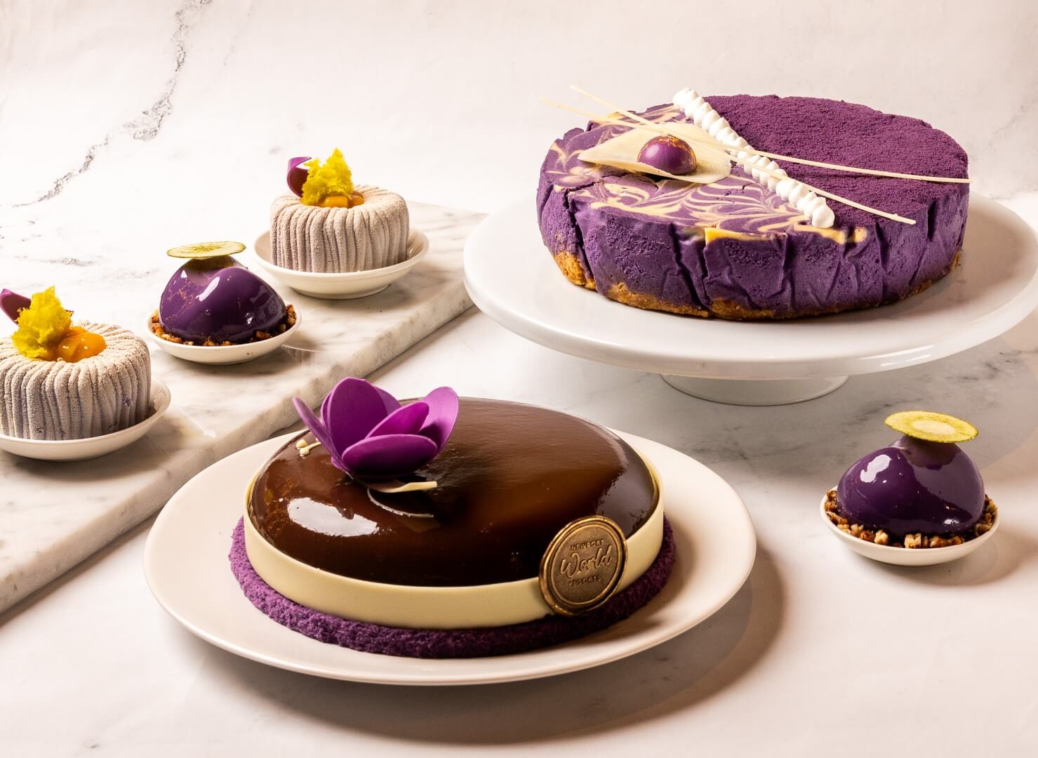 Garden Wing Café presents a selection of ube-inspired desserts, featuring Ube Pecan Chocolate Cake and Ube Coconut Cheesecake alongside individually plated desserts Golden Purple and  Velvet Earth